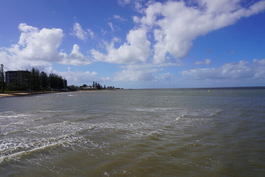 Calm ocean waves at Redcliffe beach Queensland Australia under blue sky with clouds scenic coastal view