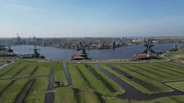 Aerial view of iconic Zaanse Schans windmills against a backdrop of calm waters and green fields, a picturesque scene, Zaandam, Noord-Holland, Netherlands.