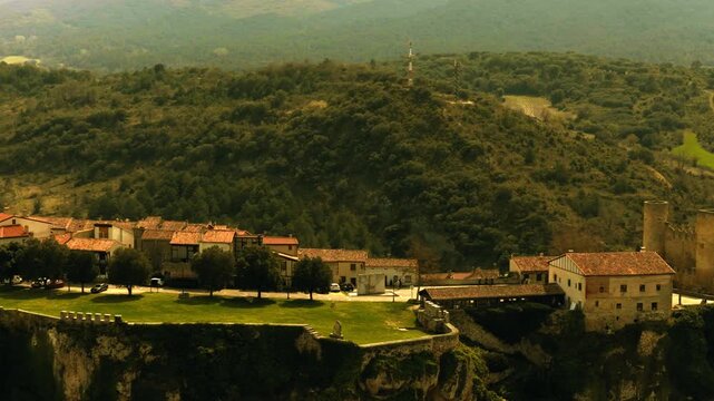 Vista a&eacute;rea cinematogr&aacute;fica del conjunto medieval de Fr&iacute;as, con etalonaje en tonos amarillos que aporta tensi&oacute;n y misterio. La arquitectura sobre la roca emerge entre sombras, evocando historia y sile