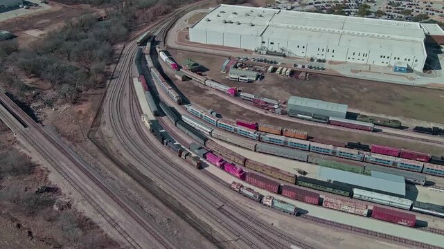 Aerial view of trains and buildings in a yard with many tracks, contrasting with the surrounding brown earth, Frisco, TX, United States.