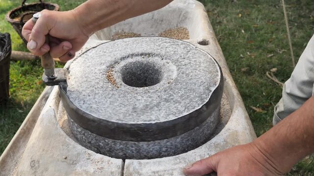 Artisan Flour Production. Closeup of Man Operating Manual Stone Mill