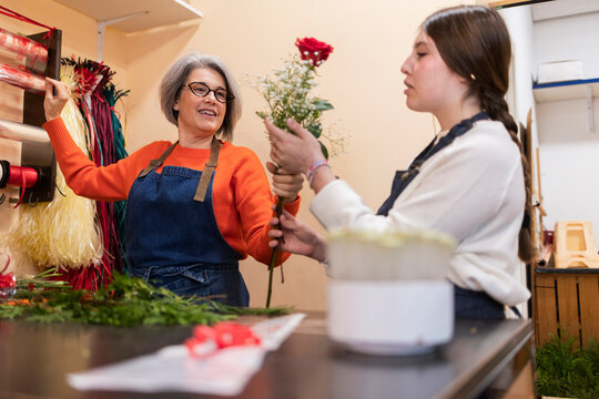 Florist and young assistant arranging flowers at a shop counter