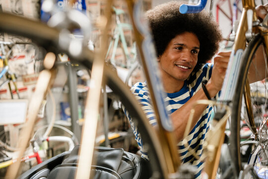 Urban bicycle mechanic repairing bike in workshop smiling