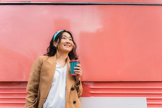 Smiling woman enjoying coffee break outdoors in urban setting