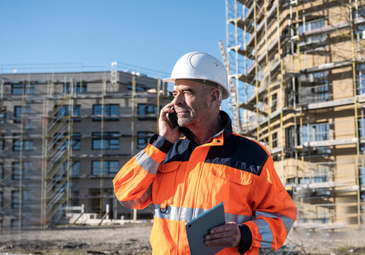 Engineer with helmet and safety jacket calling at construction site