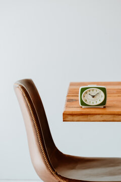 Vintage alarm clock on wooden table with chair and copy space