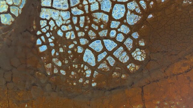 Aerial view of unique cracked mud patterns with blue mineral deposits and reddish-brown soil in the mining landscape of Minas de Riotinto, Andalusia, Spain.