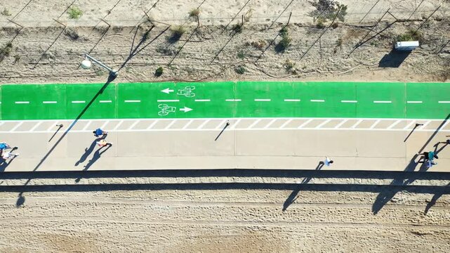 Aerial view of the vibrant green bike path contrasts with the sandy beach along Shlomo Lahat Promenade, Tel Aviv-Yafo, Tel Aviv District, Israel.