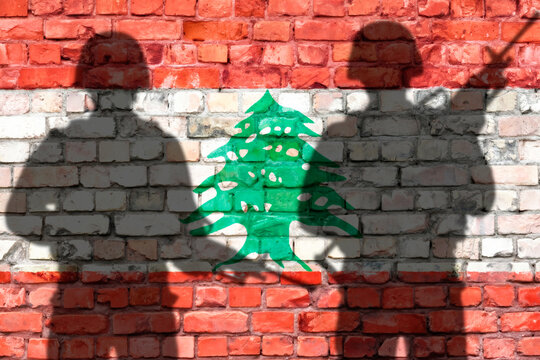 Schattenbilder von zwei Soldaten vor Ziegelwand mit Libanon-Flagge