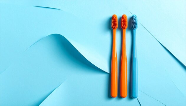 Orange Toothbrushes with Blue Bristles on Light Blue Background