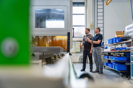 Employee and supervisor discussing next to machine in production hall