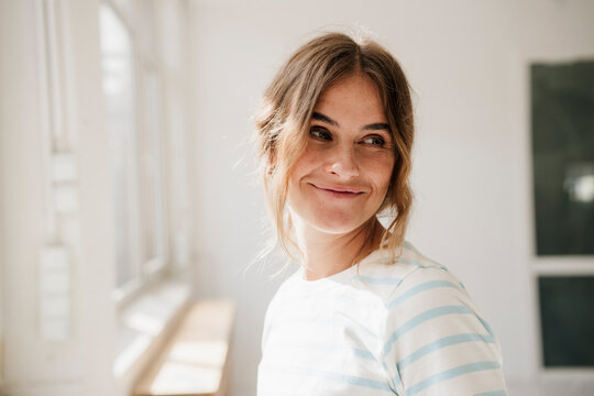 Smiling woman in striped shirt at creative studio with natural light