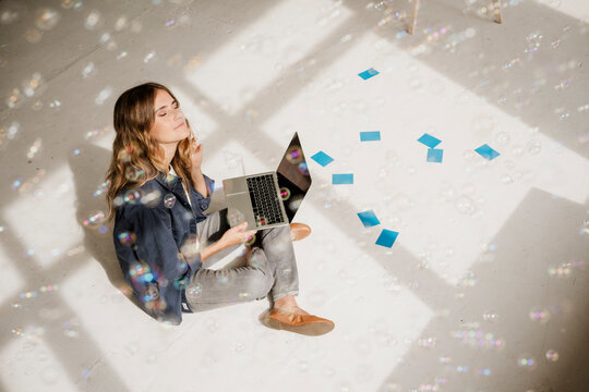 Creative woman relaxing with laptop and sticky notes in sunny studio