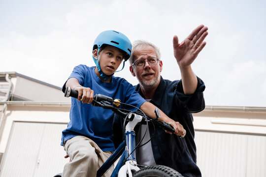 Father teaching son how to ride bike outdoors with helmet and advice