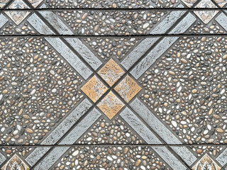 Close up tile art using combination of grey and orange tiles in diamond lines pattern, with roughcast pebble dash grabel cemented in a diagonal diamond pattern. Seamless background texture. © TMR Studio