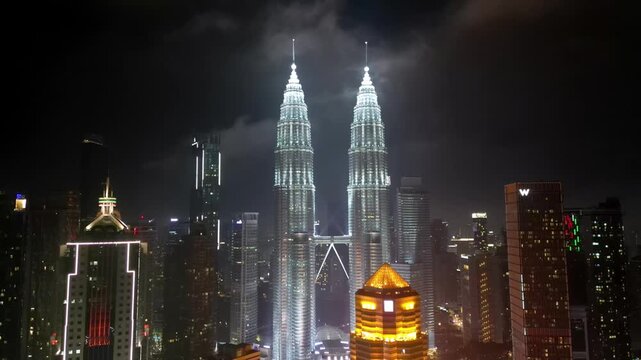Kuala Lumpur, Malaysia - 20 March 2026: Aerial view of the Petronas Towers piercing the night sky, a beacon of light amidst the cityscape's twinkling lights.