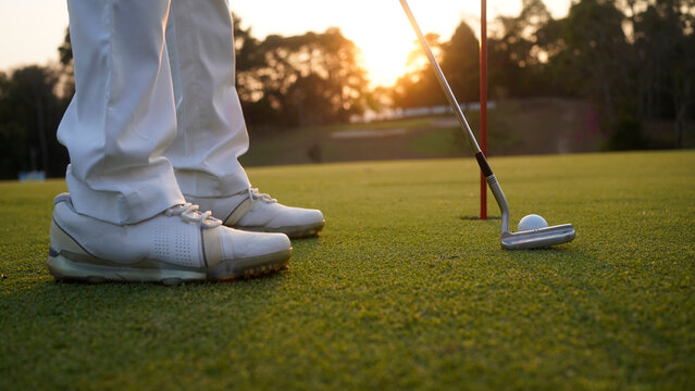 Golfer putting ball on the green golf, lens flare on sun set evening time.