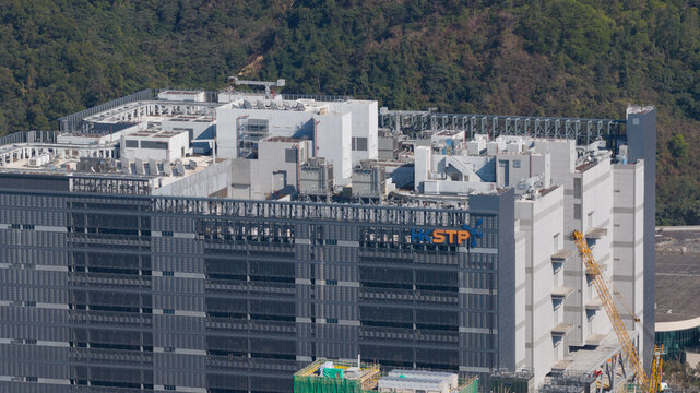 New Territories, Hong Kong - 14 February 2026: Aerial view of the Data Technology Hub building with HKSTP logo, rooftop industrial equipment, and forested hills in the background.