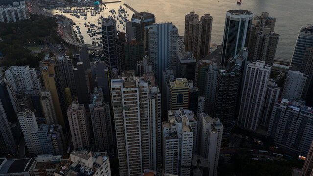 Hong Kong - 14 February 2026: Aerial view of Victoria Harbour with dense skyscrapers, residential towers, and a marina filled with yachts at dusk.