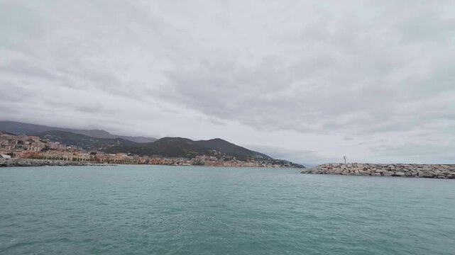 Varazze town sits along the Ligurian coastline with a harbor and Mediterranean Sea under a cloudy sky