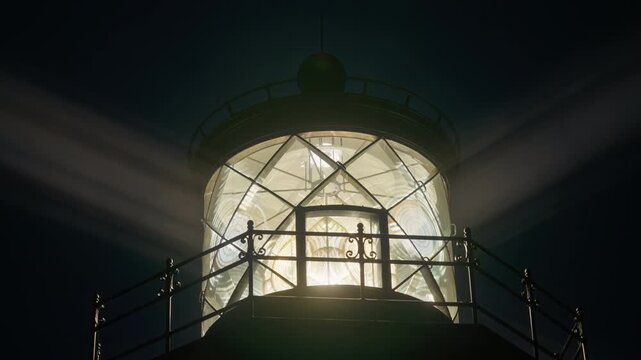 Detailed close view of lighthouse beacon with bright light rays cutting through fog at night near Mendocino, California, USA highlighting glass dome and powerful maritime signal