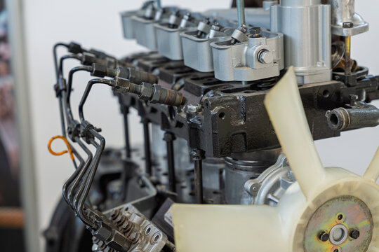 Detailed view of a disassembled diesel engine on display at a trade show, showing the fuel injection lines, rocker arms, and cooling fan, providing a technical look at internal combustion components.