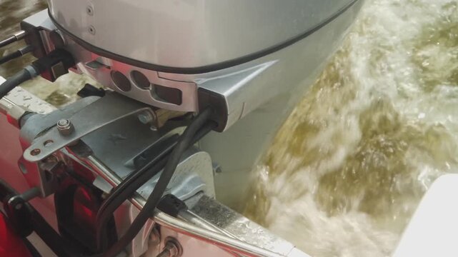 Outboard boat motor driving through water creating a wake, showing propulsion and movement on river or lake