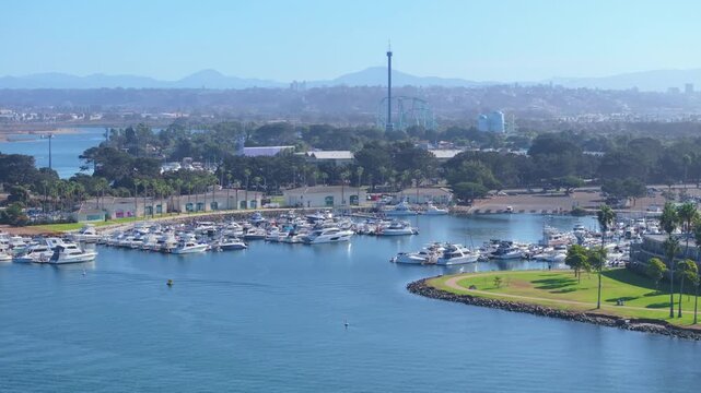 Aerial view of Mission Bay Park in San Diego California showing marina filled with luxury yachts and boats docked in calm blue water.