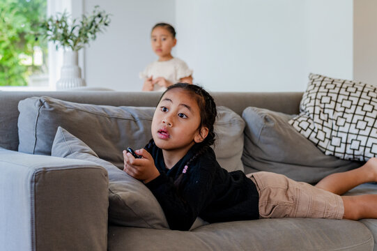 Young boy lying comfortably on the couch holding a remote control