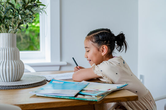 Young Samoan girl sitting behind wooden table doing her homework