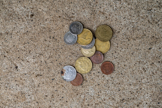A mix of New Zealand coins scattered on a speckled concrete surface