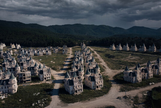 View of the abandoned chateau-style villas of Burj Al Babas nestled against forested hills under a dramatic cloudy sky in Dolayuz, Bolu, Turkiye.