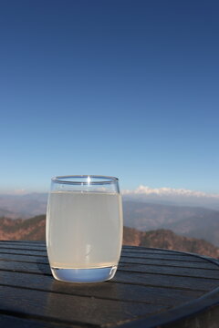 Traditional Indian lemon drink Nimbu Pani with fresh lime, mint and ice in a glass, refreshing summer beverage with scenic snow-covered mountains in the background.