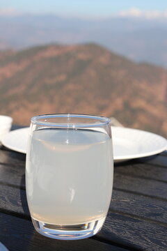 Traditional Indian lemon drink Nimbu Pani with fresh lime, mint and ice in a glass, refreshing summer beverage with scenic snow-covered mountains in the background.