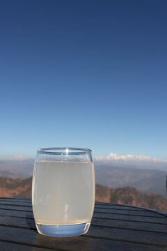 Traditional Indian lemon drink Nimbu Pani with fresh lime, mint and ice in a glass, refreshing summer beverage with scenic snow-covered mountains in the background.