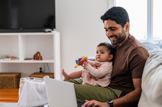 Parent multitasking with baby and laptop on couch