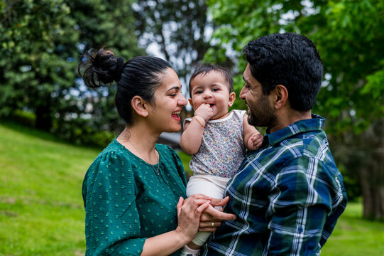 A couple with their child spending quality time together, standing closely at a park at daytime