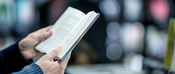 Man reading book in the city street, detail on the hands