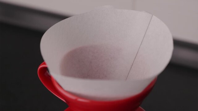 Placing paper filter into red V60 dripper close-up