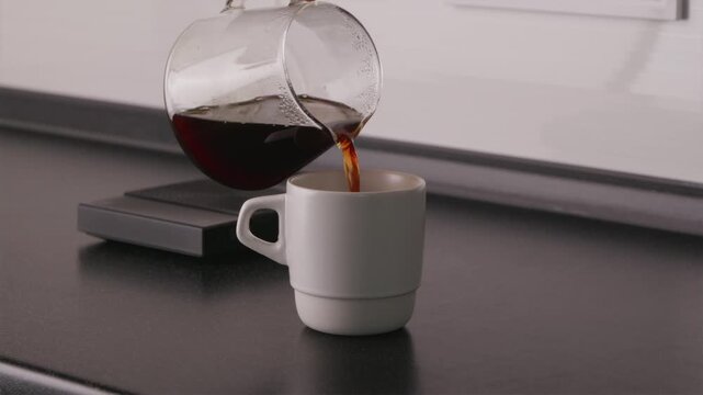 Pouring fresh filter coffee from glass server into white cup