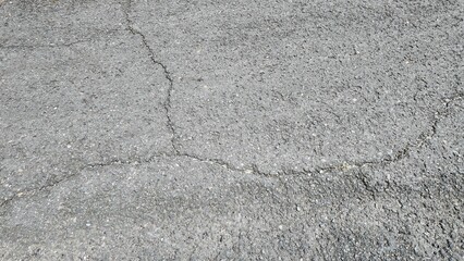 Obraz premium Textured surface of cracked asphalt with varied shades of gray and black creating a natural pattern