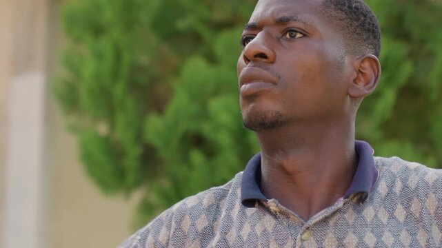 Athlete prepares outdoors with calm concentration. Man concentrates on warmup during outdoor training session. Focused athlete in patterned polo calmly prepares for vigorous outdoor workout