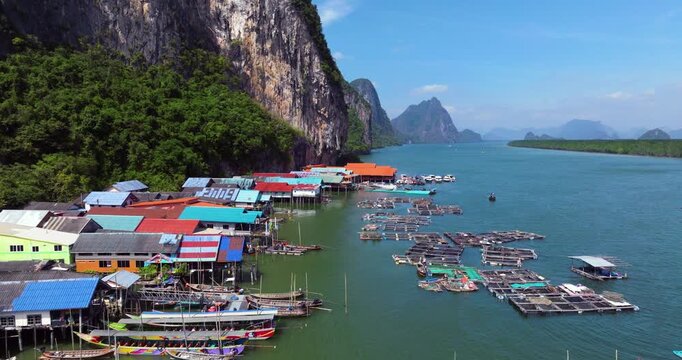 Aerial View Of Koh Panyee Floating Village In Thailand's Phang Nga Bay, With Colorful Stilt Houses And Fishing Nets Along Limestone Cliffs.