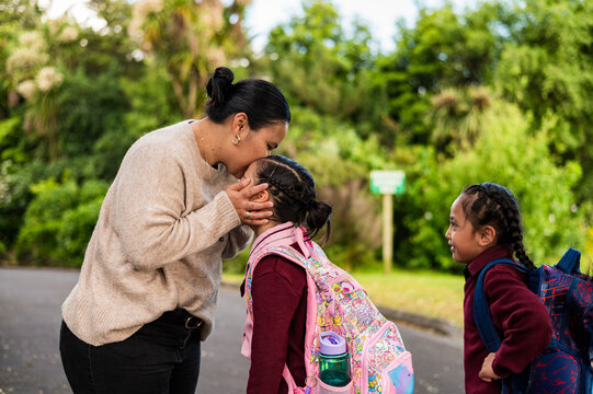 Niuean mum bending down holding daughters face and giving a soft kiss