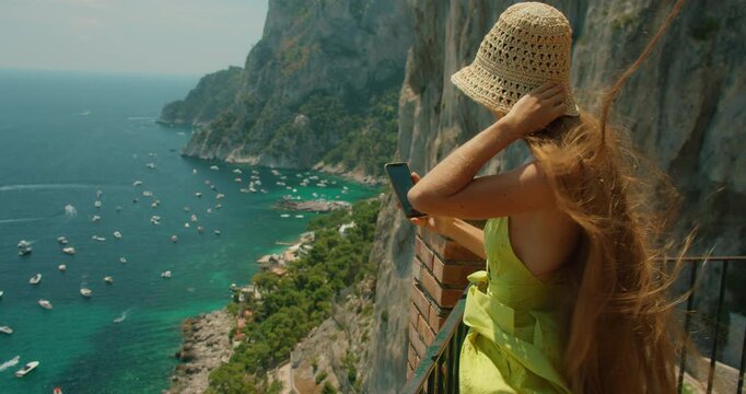 Woman admires the view of Marina Piccola from a cliffside terrace in Capri Italy in summer