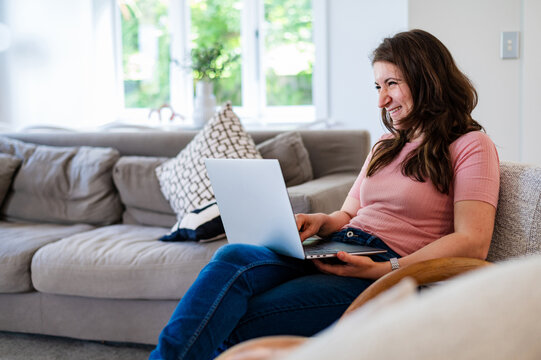 Italian woman sitting on a couch working on her laptop inside home
