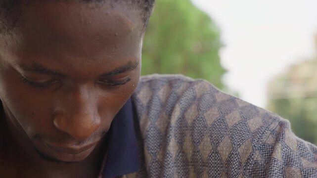 Black man closeup focused study, downward gaze with detailed skin texture and subtle sweat, quiet concentration. Sequence shows reader scanning lines, craftsman inspecting tool, thinker absorbed