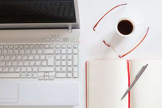 Postazione di lavoro con computer, notes, occhiali e tazzina di caff&egrave;