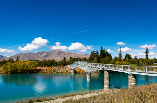view of a walk bridge over blue water with mountain in the distance