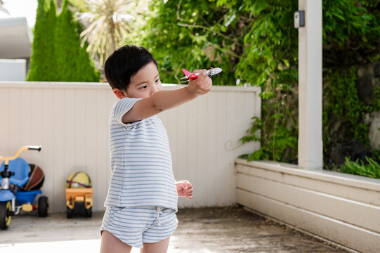Young Asian boy playing with a toy aeroplane in the patio